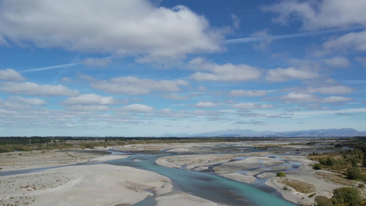 夏季，从广阔的怀马卡里里河(wamakariri River)上空俯瞰，远处是南阿尔卑斯山的山麓(新西兰坎特伯雷)。视频素材