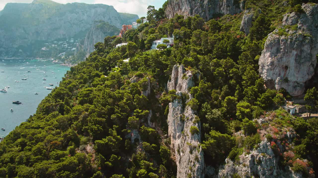 郁郁葱葱的绿色植物覆盖着卡普里岛的风景，蓝色的海面上点缀着船只。意大利充满活力的夏日冒险。视频素材