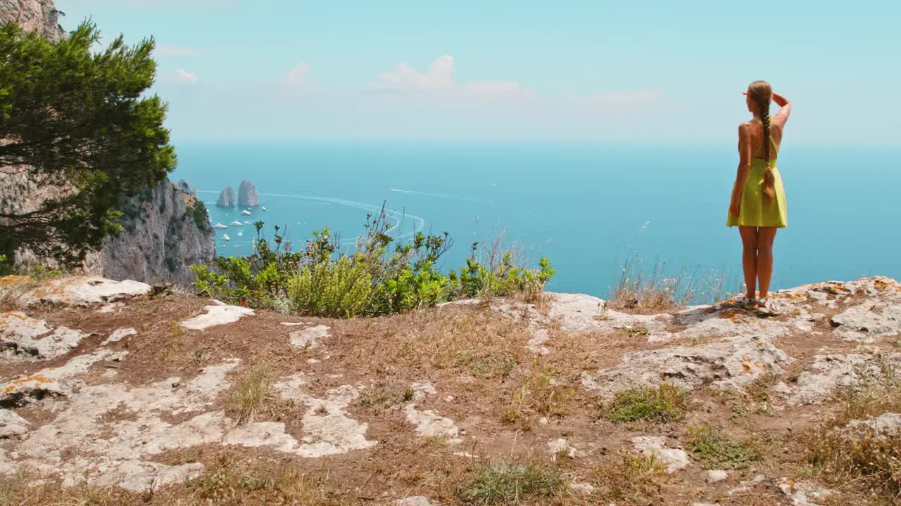 游客探索卡普里岛崎岖的地形。徒步旅行者俯瞰宁静的海湾与法拉格里奥尼岩石。意大利的夏季海洋天堂。视频素材