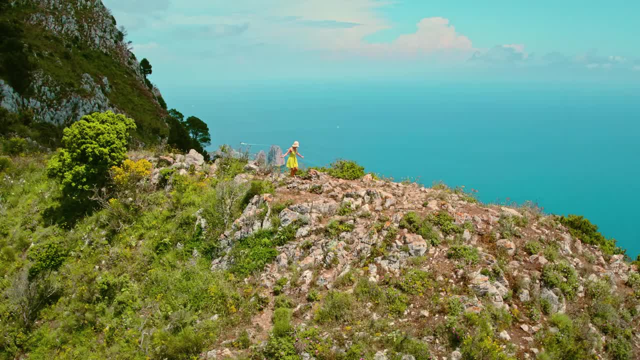 徒步旅行者观察风景秀丽的海岸悬崖和绿松石海。一名女子走在悬崖边，望着满是船只的大海。视频素材