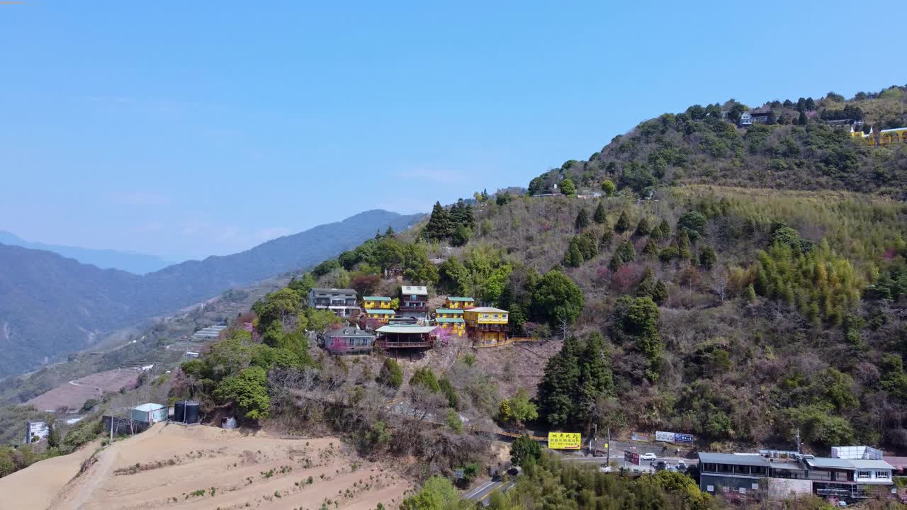 色彩缤纷的建筑坐落在森林覆盖的山坡上，蓝天，鸟瞰视频素材