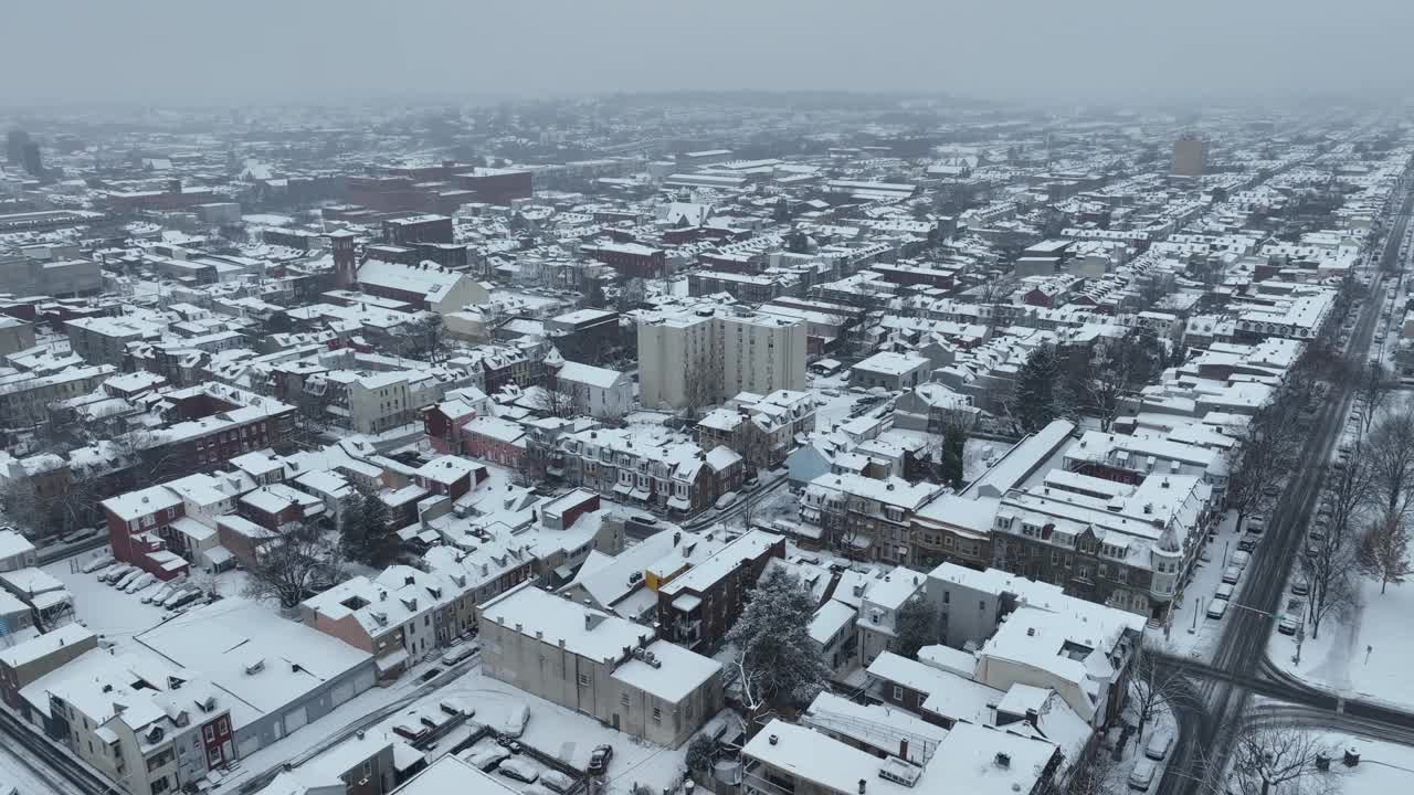 无人机在美国小镇上有房子和街区的积雪城市上空飞行。寒冷冬日里的乌云。空中天桥。视频素材