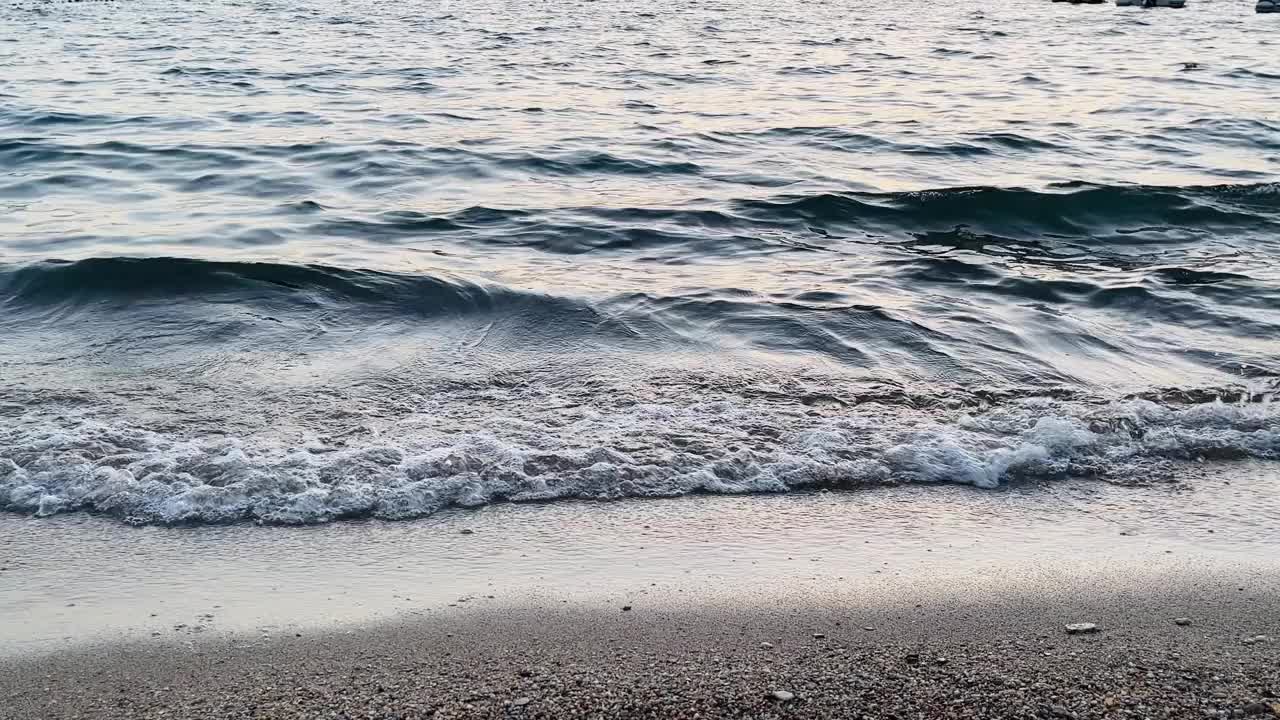 黄昏时，柔和的海浪冲刷着鹅卵石沙滩，夏日出游视频素材