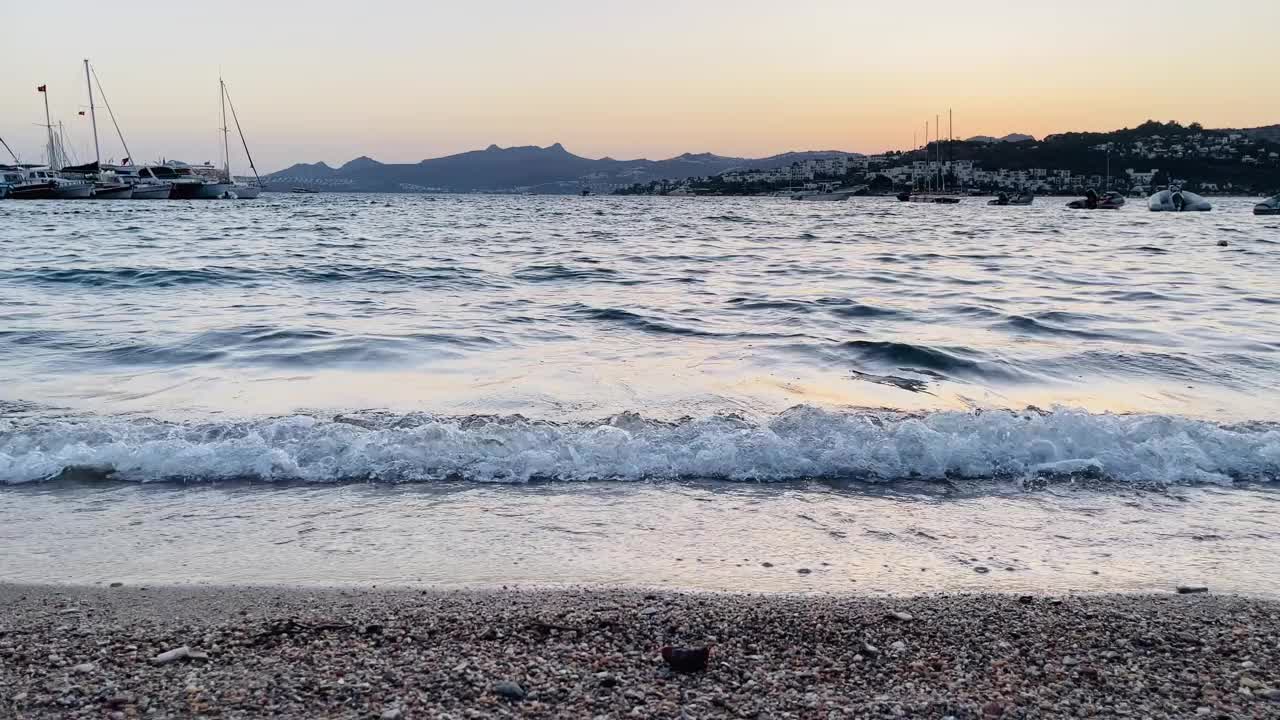 黄昏时，柔和的海浪冲刷着鹅卵石沙滩，夏日出游视频素材