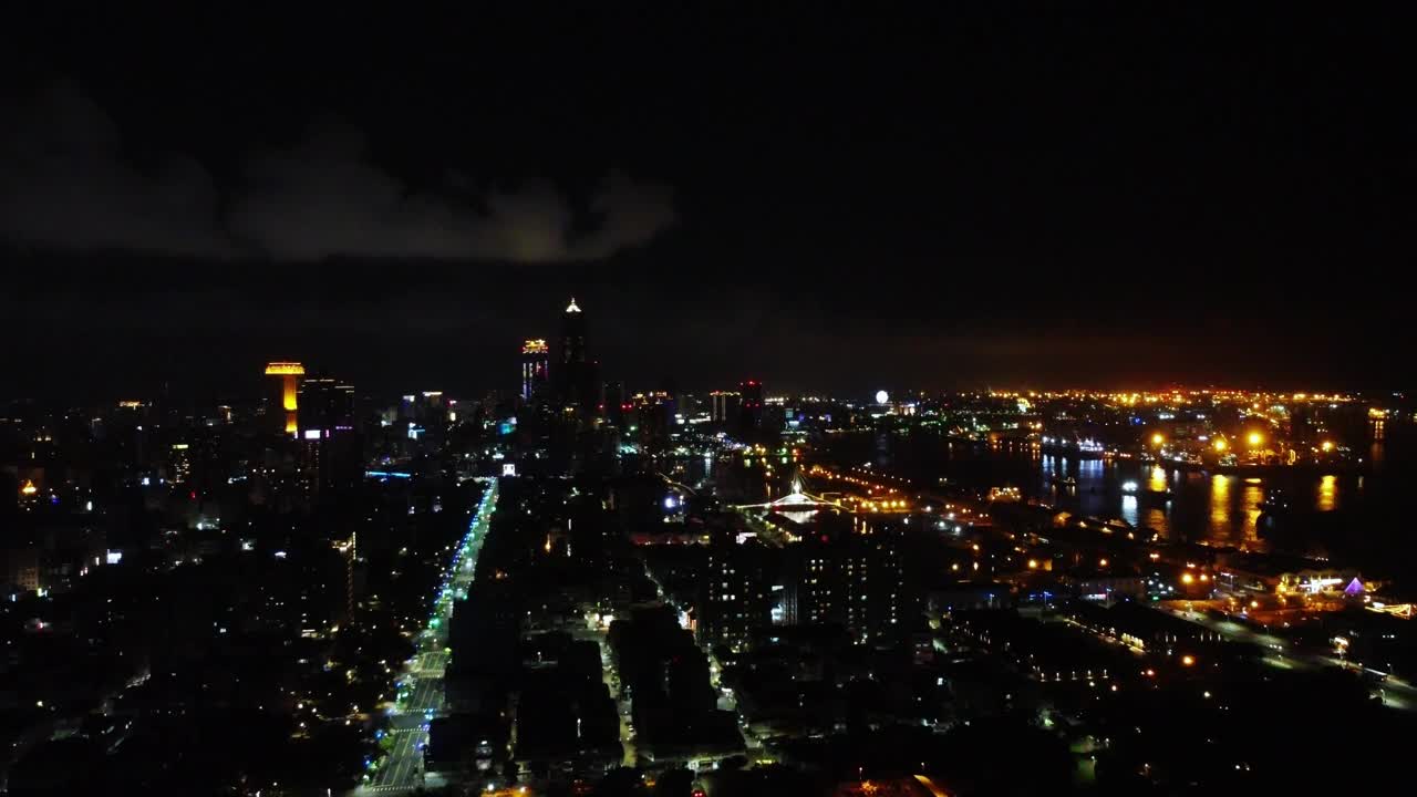 夜间鸟瞰熙熙攘攘的城市景观，沿河的街道和建筑物灯火通明视频素材