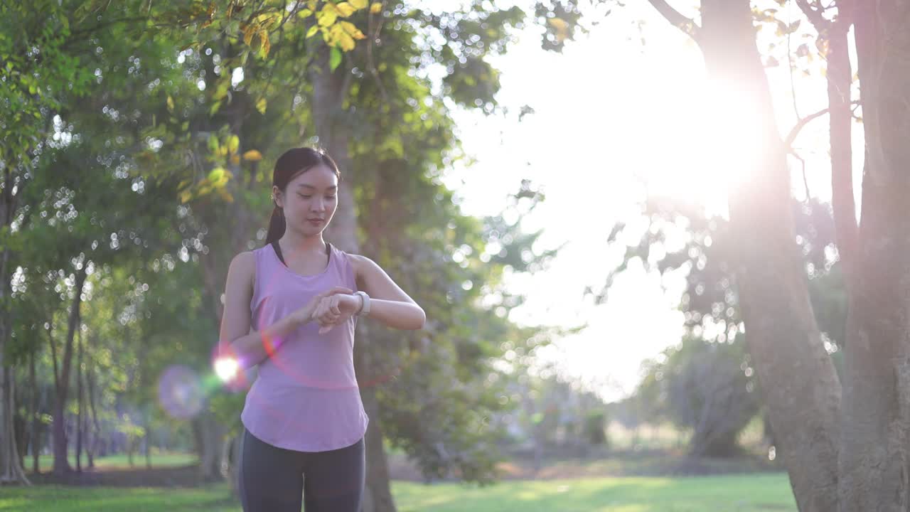 年轻美丽的亚洲女人正在公园的树下慢跑。视频素材