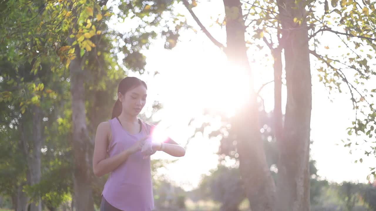 年轻美丽的亚洲女人正在公园的树下慢跑。视频素材