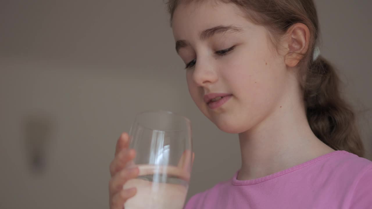 女孩从杯子里喝干净的水。儿童女孩在家里饮用玻璃新鲜透明纯过滤矿泉水。特写孩子喝杯水健康的身体护理。健康的生活方式。视频素材