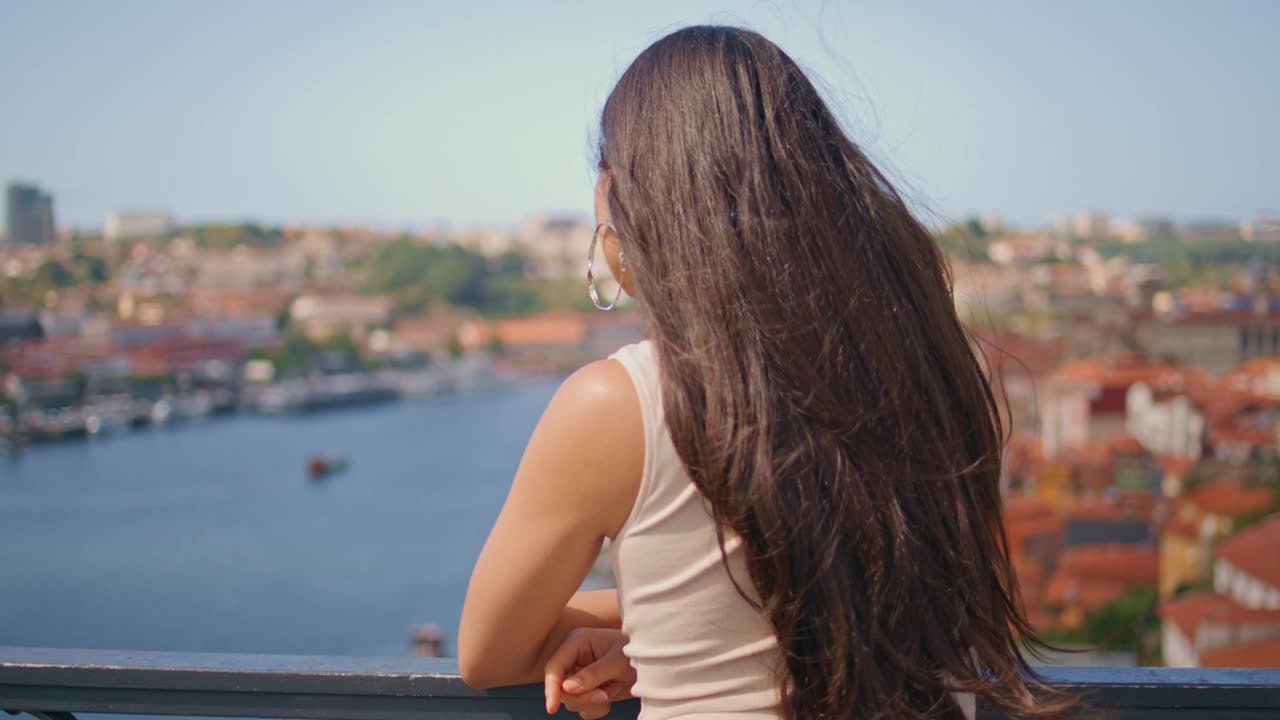 深色头发的女人把摄像头转向河桥的后景。沉思水的女士视频素材