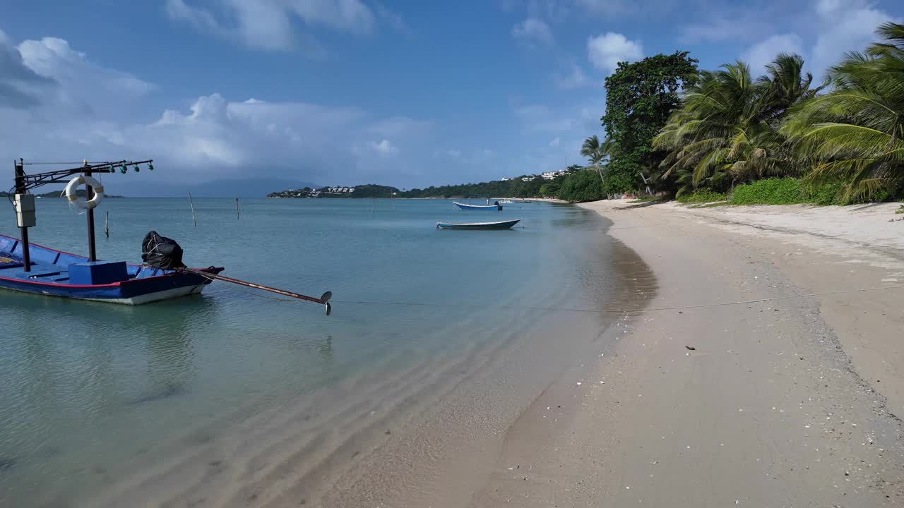 宁静的泰国海滩与船在晴朗的日子，金色的沙滩弯曲成郁郁葱葱的绿色植物，宁静的海景视频素材