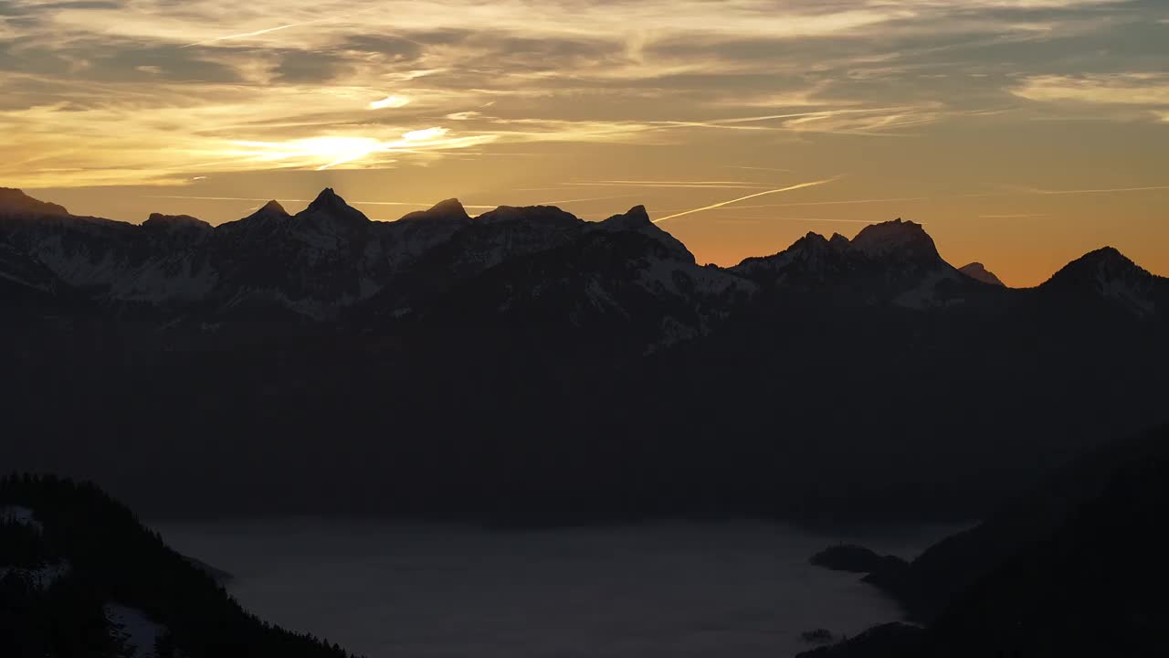 黄昏笼罩着格拉鲁斯的阿姆登山脉，轮廓映衬着火红的天空，宁静而雄伟，广角镜头视频素材