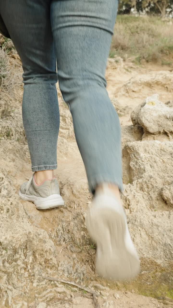 垂直视频。镜头跟随一名妇女在岩石间的山路上徒步旅行。旅游走。视频素材