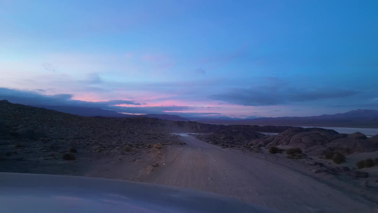 夕阳下尘土飞扬的沙漠之路，智利彩色天空下的汽车视角视频素材