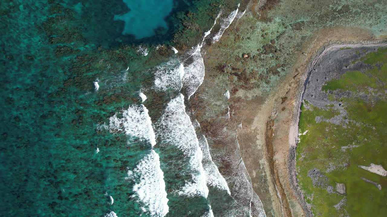 清澈的海水和波浪破碎的珊瑚礁，倾斜到崎岖的海岸，鸟瞰图视频素材