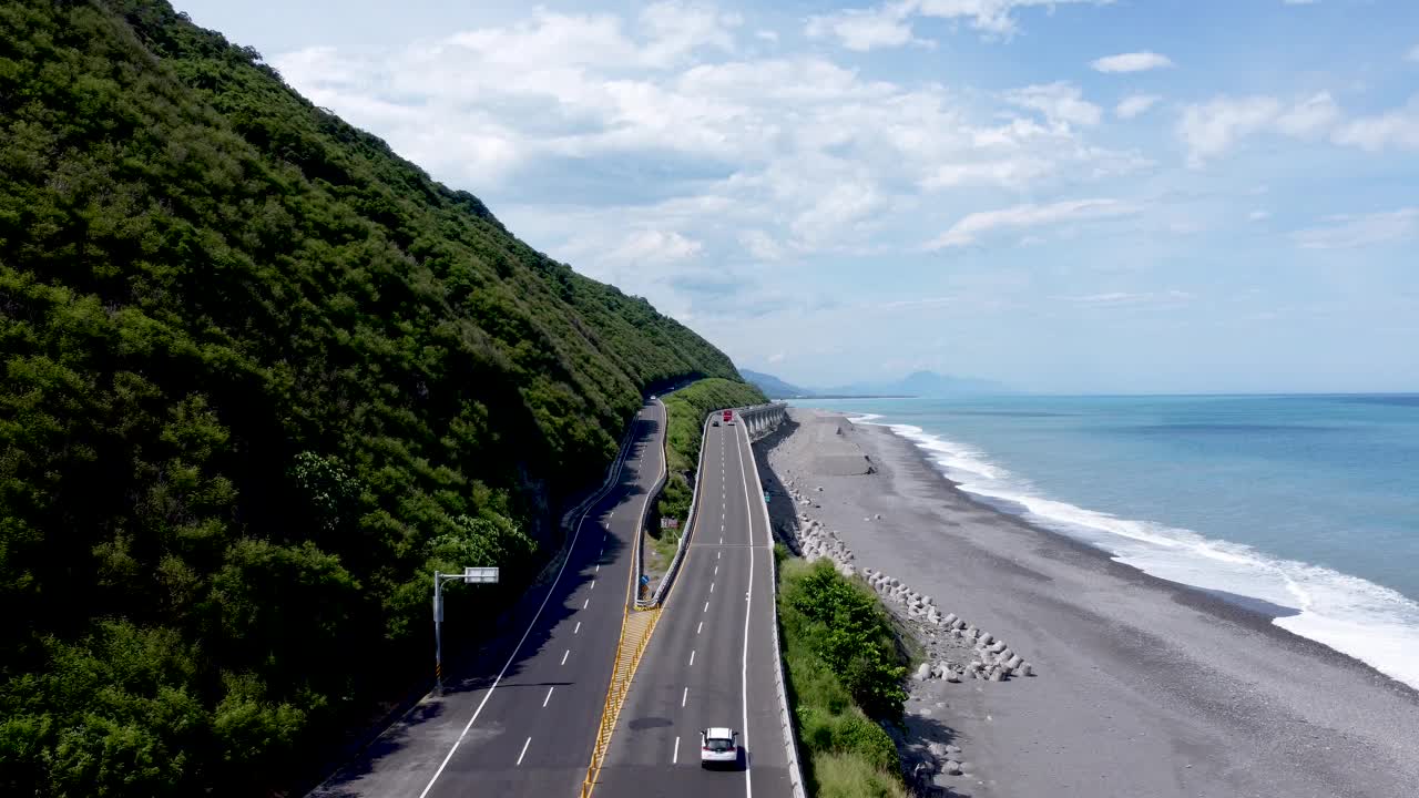 沿海道路沿着郁郁葱葱的山坡和海滩弯曲，阳光明媚的蓝色大海，航拍视频素材