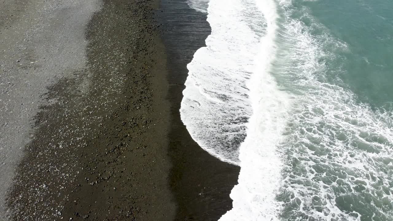 海浪轻轻地冲刷着黑色的沙滩，鸟瞰图视频素材