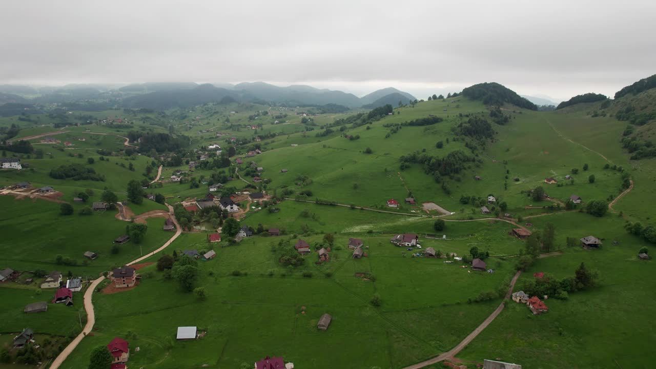 郁郁葱葱的青山点缀着阴天下的乡村，鸟瞰图视频素材