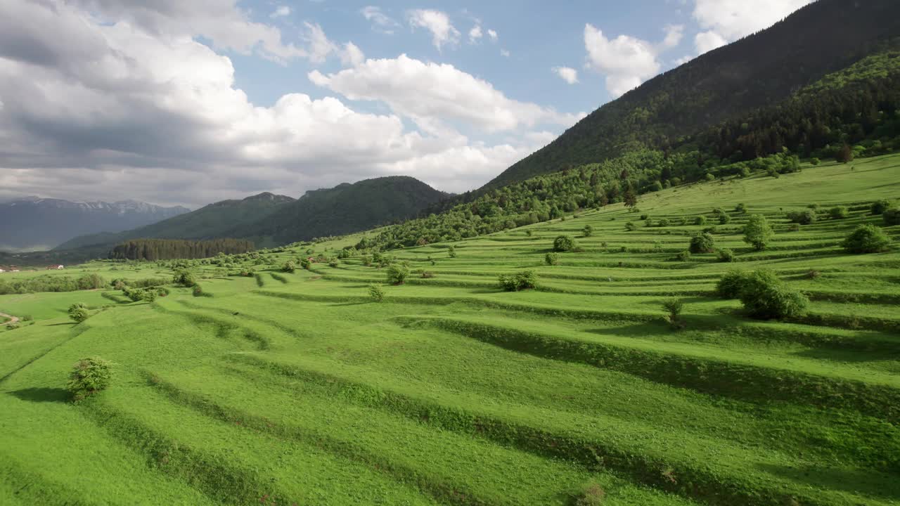 郁郁葱葱的梯田和多云的天空下的群山，暗示着农村农业视频素材