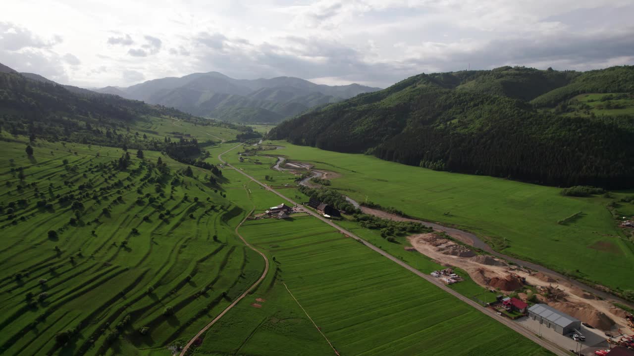 航拍的绿油油的山谷、梯田和乡村道路，多云的天空视频素材