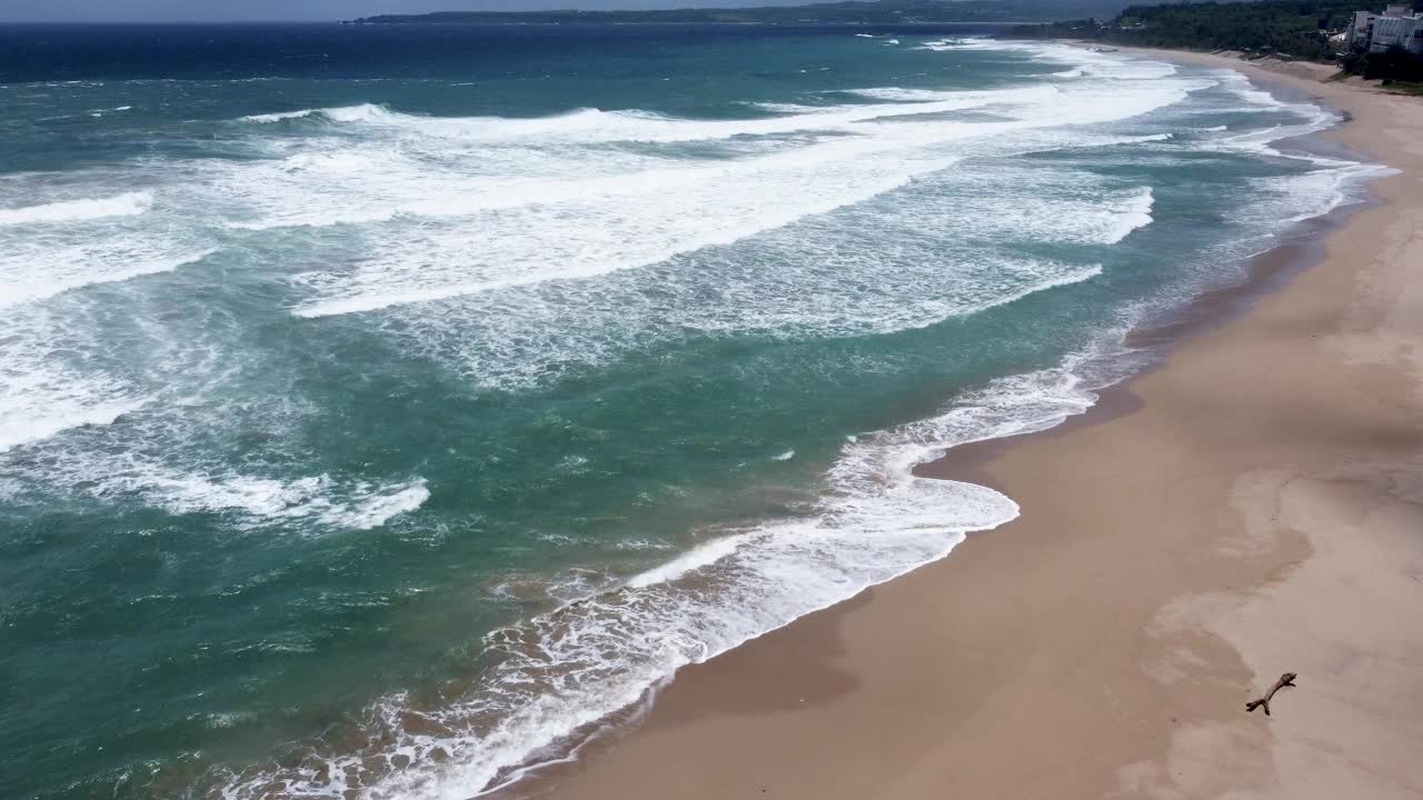 宁静的海岸线，海浪抚摸着金色的沙滩，鸟瞰视频素材