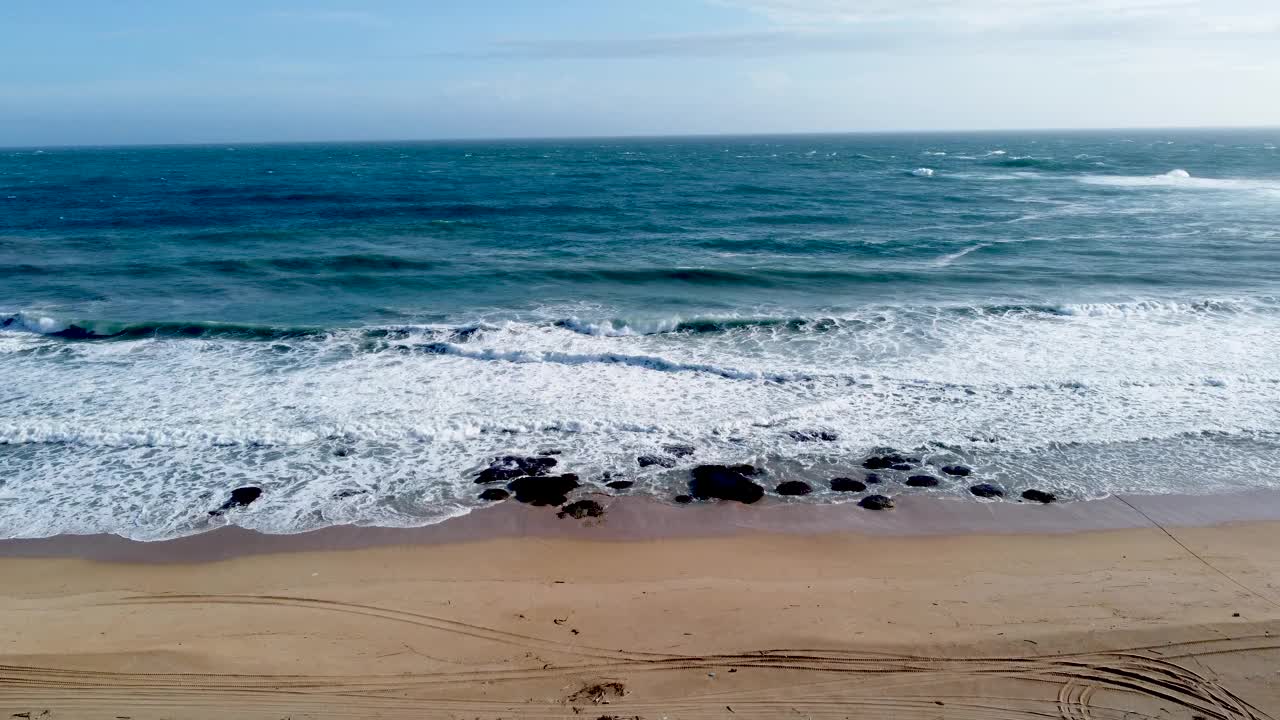 海浪拍打着沙滩上的岩石，晴朗的天空，鸟瞰图视频素材