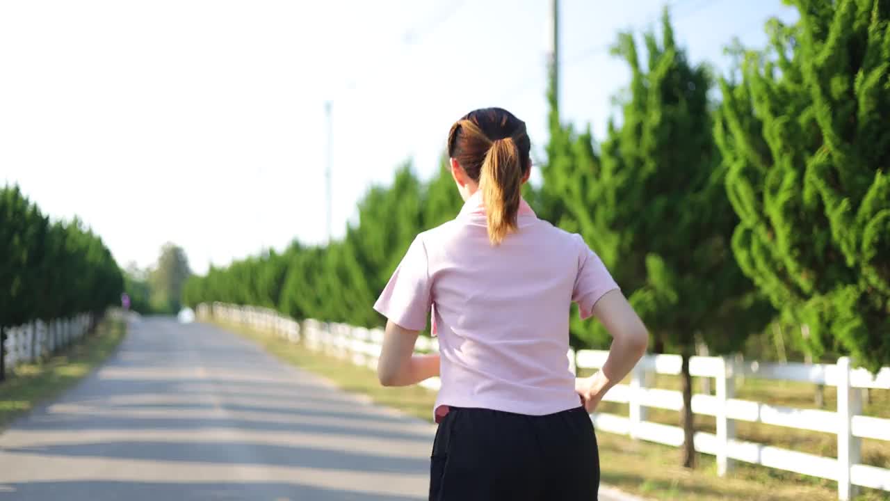 年轻漂亮的亚洲女人身体健康，正在公园的路上慢跑。视频素材