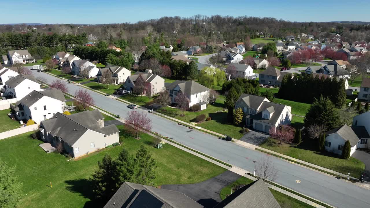 阳光明媚的日子里，美国郊区的一排中产阶级住宅。笔直的街道，背景是森林山丘。美国宾夕法尼亚州安静的美国社区。空中轨道拍摄。视频素材