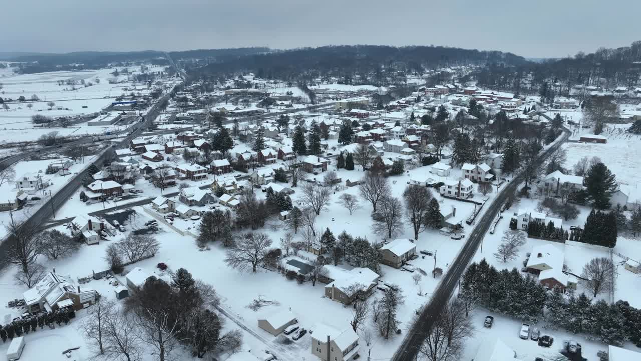 鸟瞰白雪覆盖的乡村小镇，道路在房屋之间交叉。视频素材