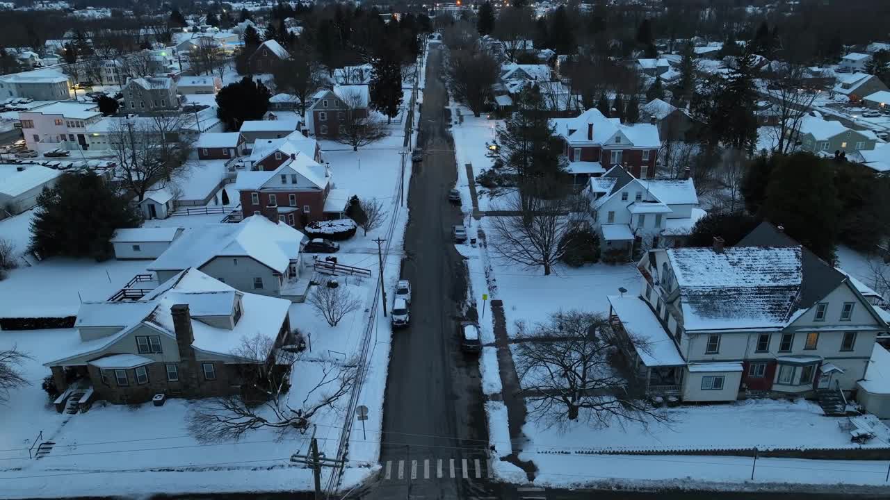 美丽的白雪覆盖的美国小镇，在金色的日落笔直的道路。美国冬天的雪。空中倾斜的广角镜头。视频素材