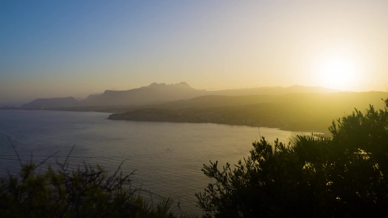 朦胧的太阳把晴朗的夏日天空染成了美丽的西班牙海岸景色视频素材