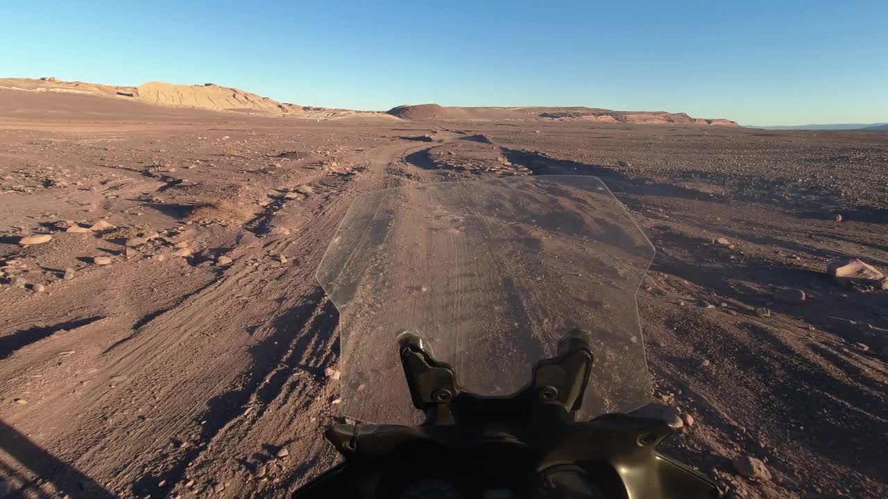 POV:摩托骑手在智利崎岖的砾石沙漠路上开过车辙视频素材