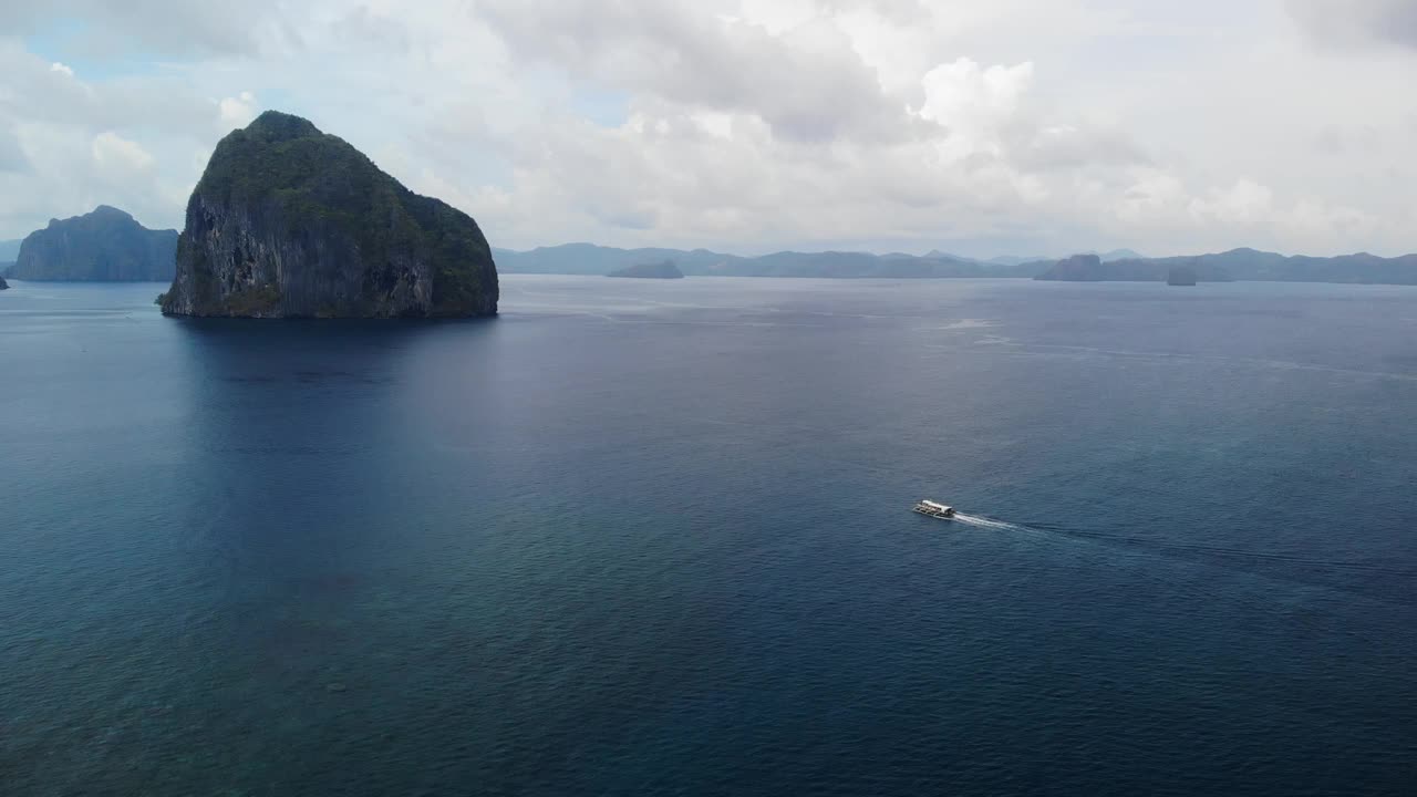 一艘船驶向一个多岩石的岛屿的鸟瞰图视频素材