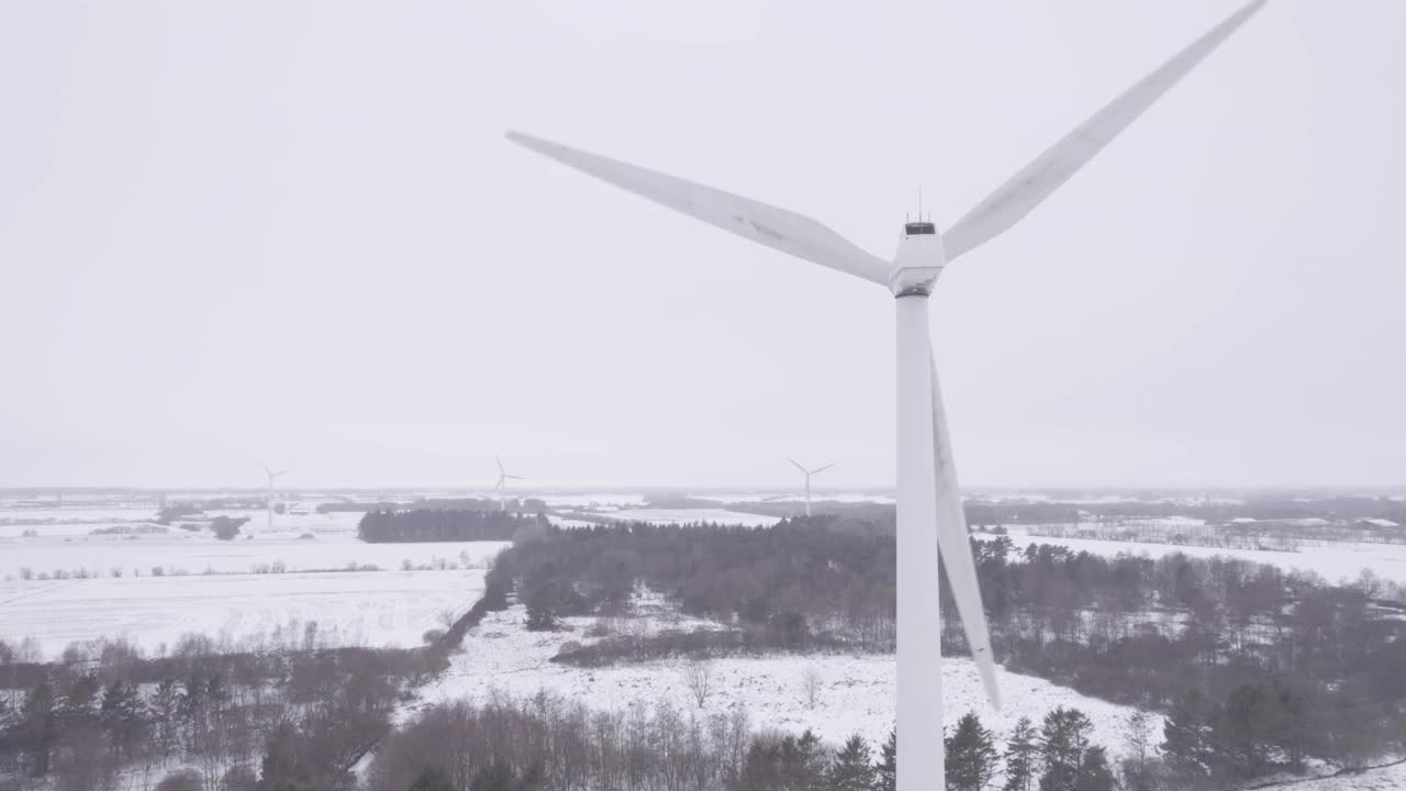 在冬季多雪的乡村，风力涡轮机产生清洁能源。航空静态拍摄视频素材