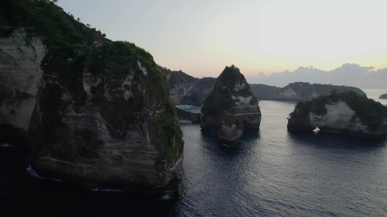 在印度尼西亚巴厘岛努沙佩尼达的日落时分，飞越石灰岩悬崖，飞往钻石海滩。无人机拍摄的视频素材