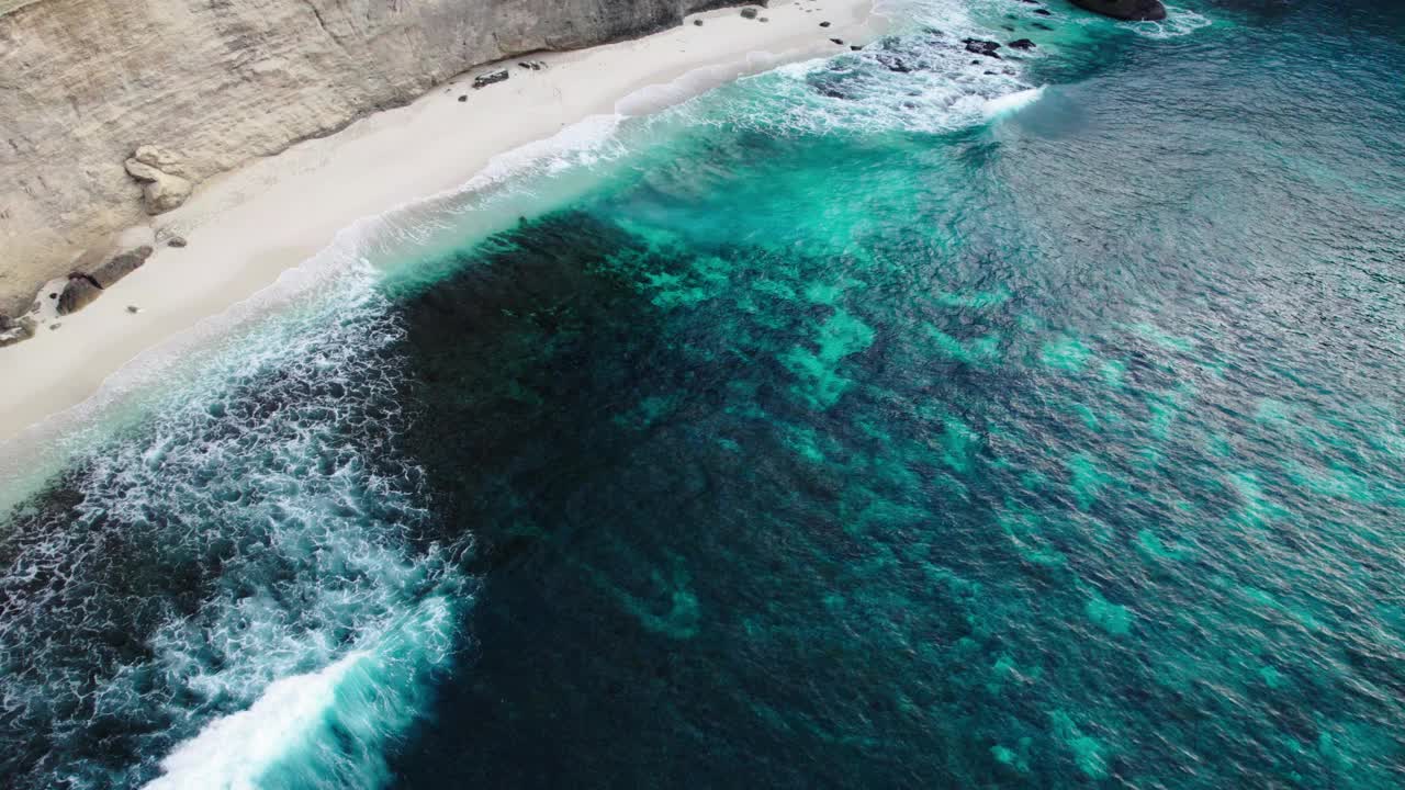 蓝绿色的海洋，海浪拍打在白色的沙滩上，巴厘岛，印度尼西亚。空中拍摄视频素材