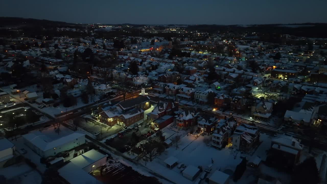 温暖的灯光雪城在美国的冬雪之夜。在路上开车。被照亮的城市景观的航拍轨道照片。视频素材