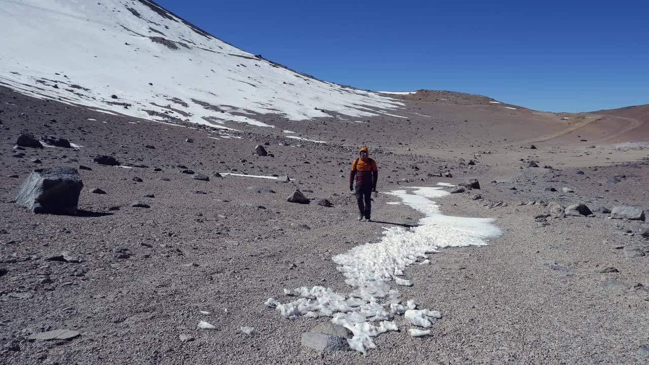 一名男性徒步旅行者在遥远的雪山风景中走向相机视频素材