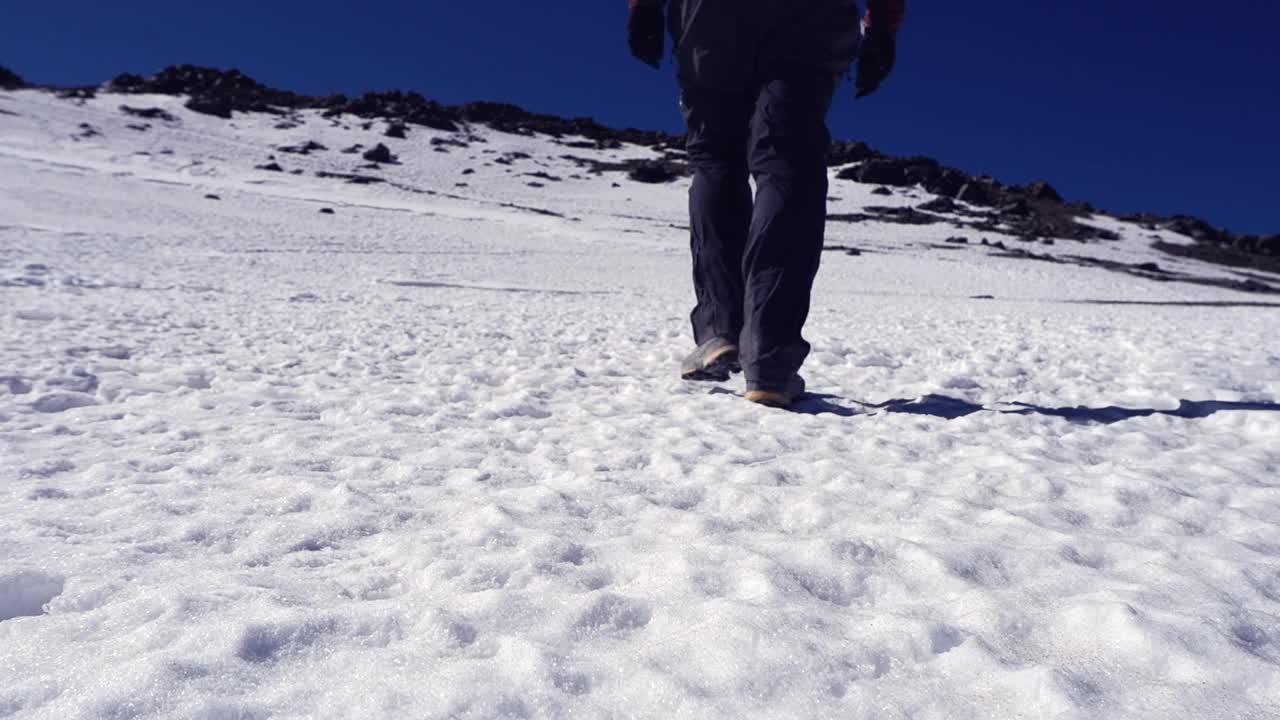 低角度:孤独的徒步者在雪地上走向遥远的山峰山脊视频素材