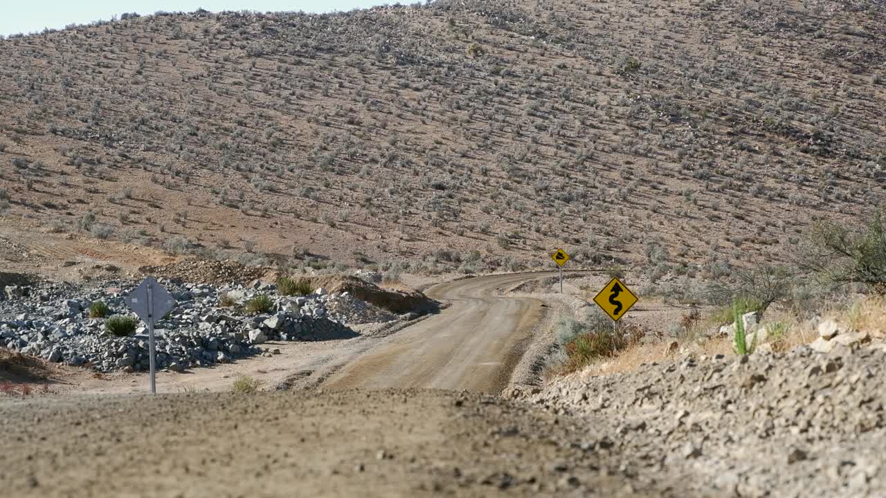 在智利偏远的乡村砾石路上，摩托车手接近相机视频素材