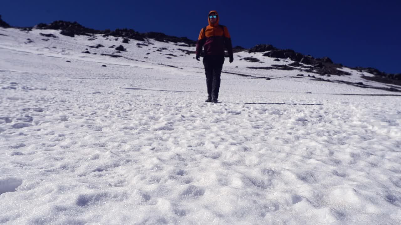 低角度徒步旅行者走到相机从雪山山脊，蓝天视频素材