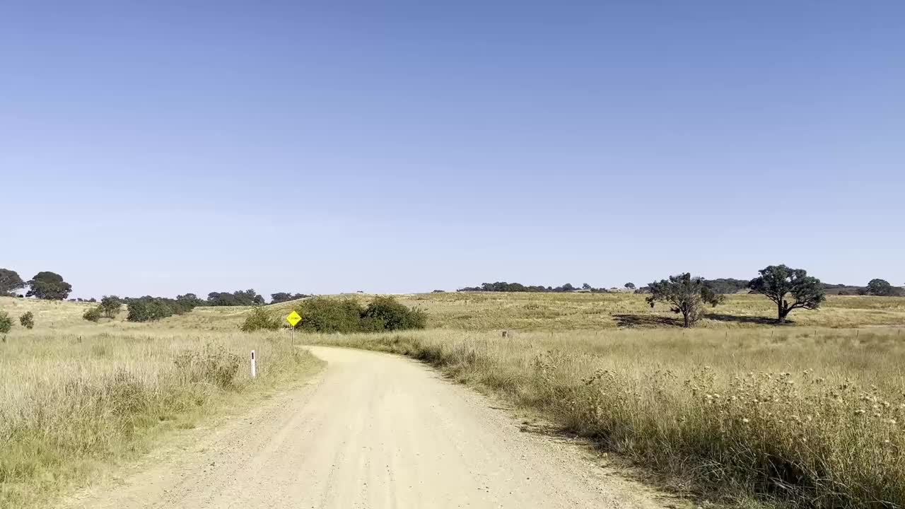 在新南威尔士州的亚斯地区，一条土路一直延伸到远处，显示出广阔的农田视频素材