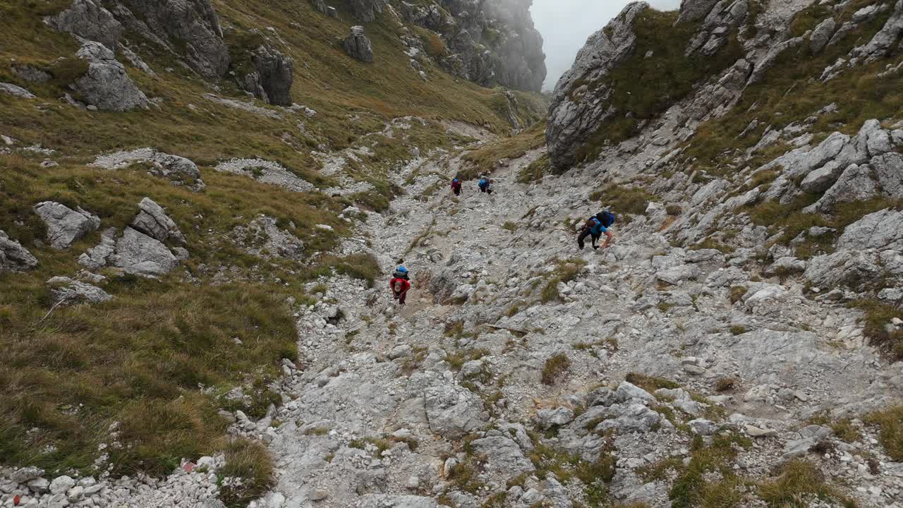 四名徒步旅行者在意大利北部的雷塞戈内岩石山徒步旅行，背景是云视频素材