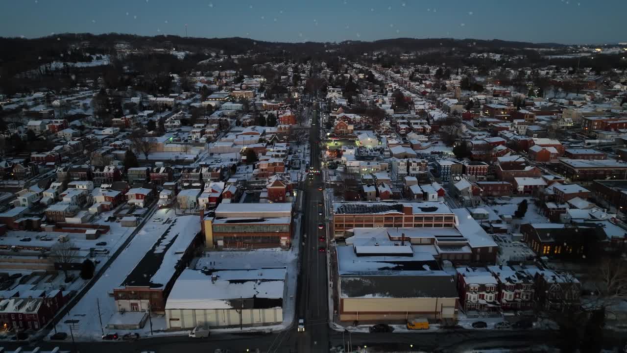 在美国的冬季，美国小镇上空飘着雪花。黄昏照亮了白色的城市。历史小镇的圣诞节。航拍鸟瞰图。视频素材