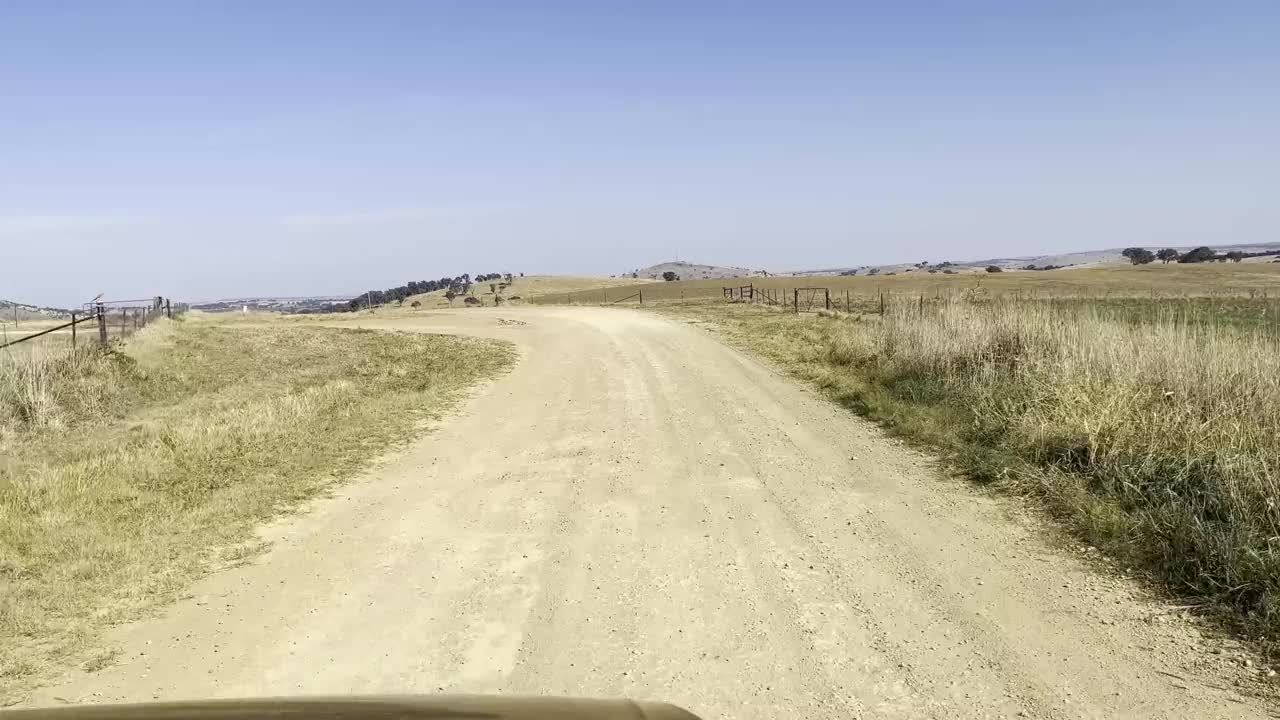 在新南威尔士州的亚斯地区，一条土路一直延伸到远处，显示出广阔的农田视频素材