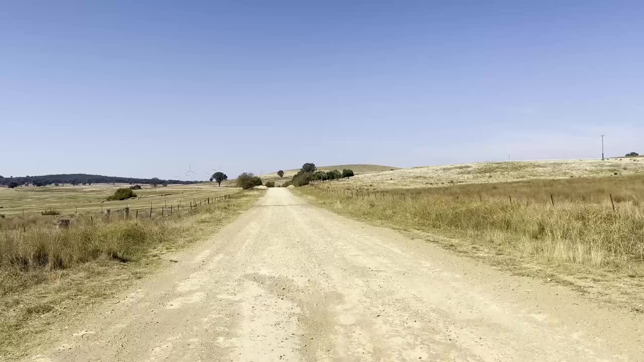 在新南威尔士州的亚斯地区，一条土路一直延伸到远处，显示出广阔的农田视频素材