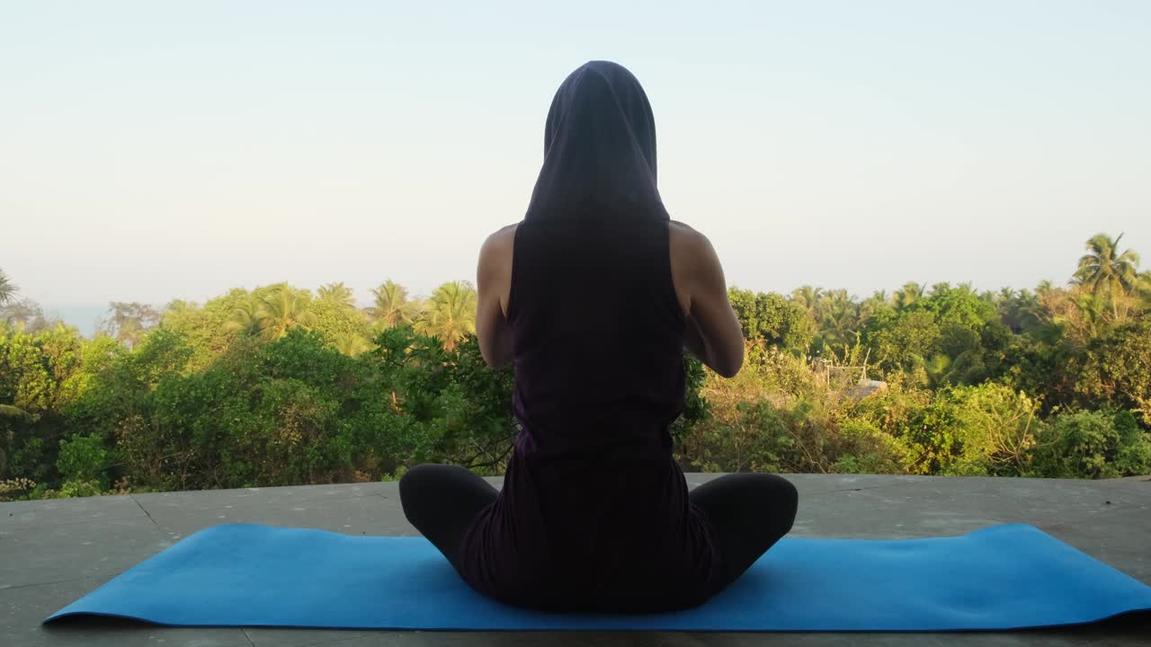 一名专注的成年女子在户外做莲花式深呼吸瑜伽练习。女性早晨在寺庙里冥想，以求身心健康。视频素材