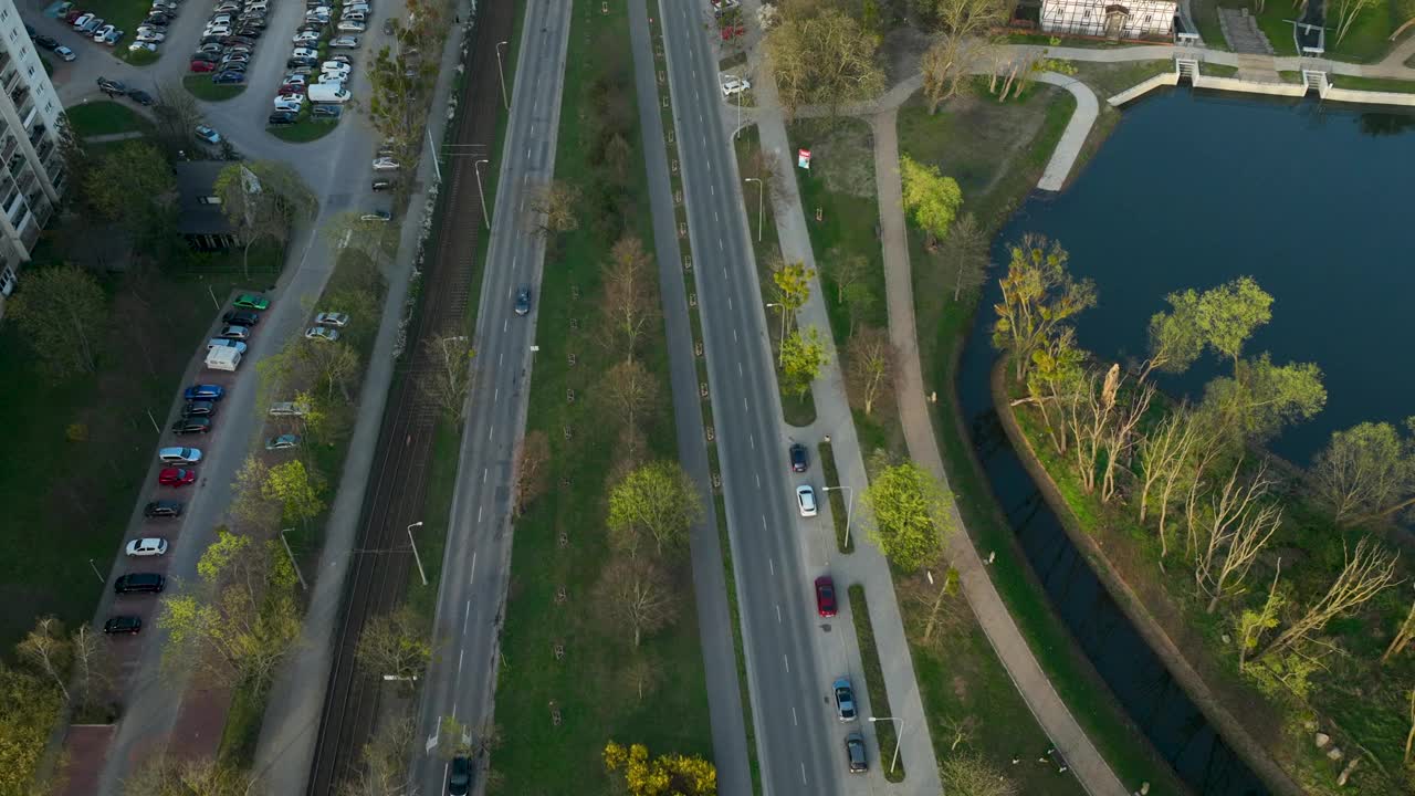 日落时分，无人机在湖边的城市道路上降落。日落时分的波兰格但斯克镇。倾斜下来。视频素材