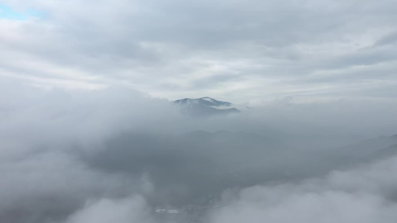 无人机在浓雾笼罩的山村上空飞行视频素材