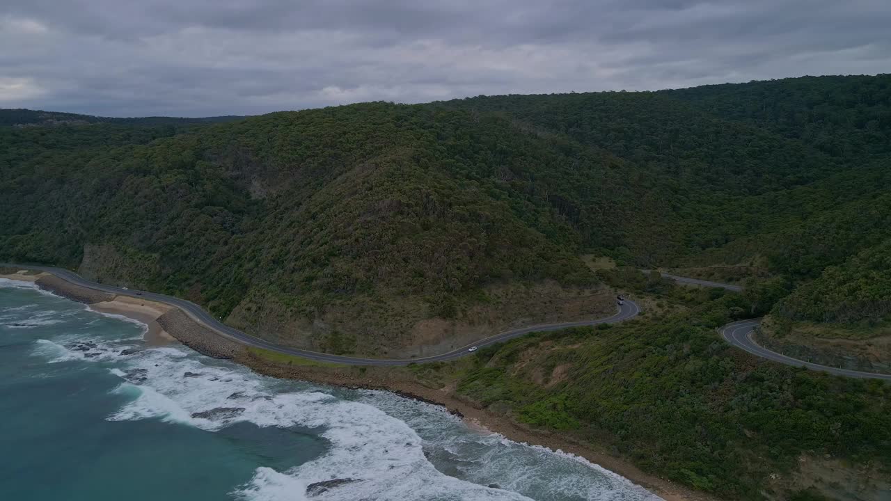 倾斜无人机鸟瞰图著名的大洋路沿海公路与汽车交通和森林山脉，维多利亚州，澳大利亚视频素材