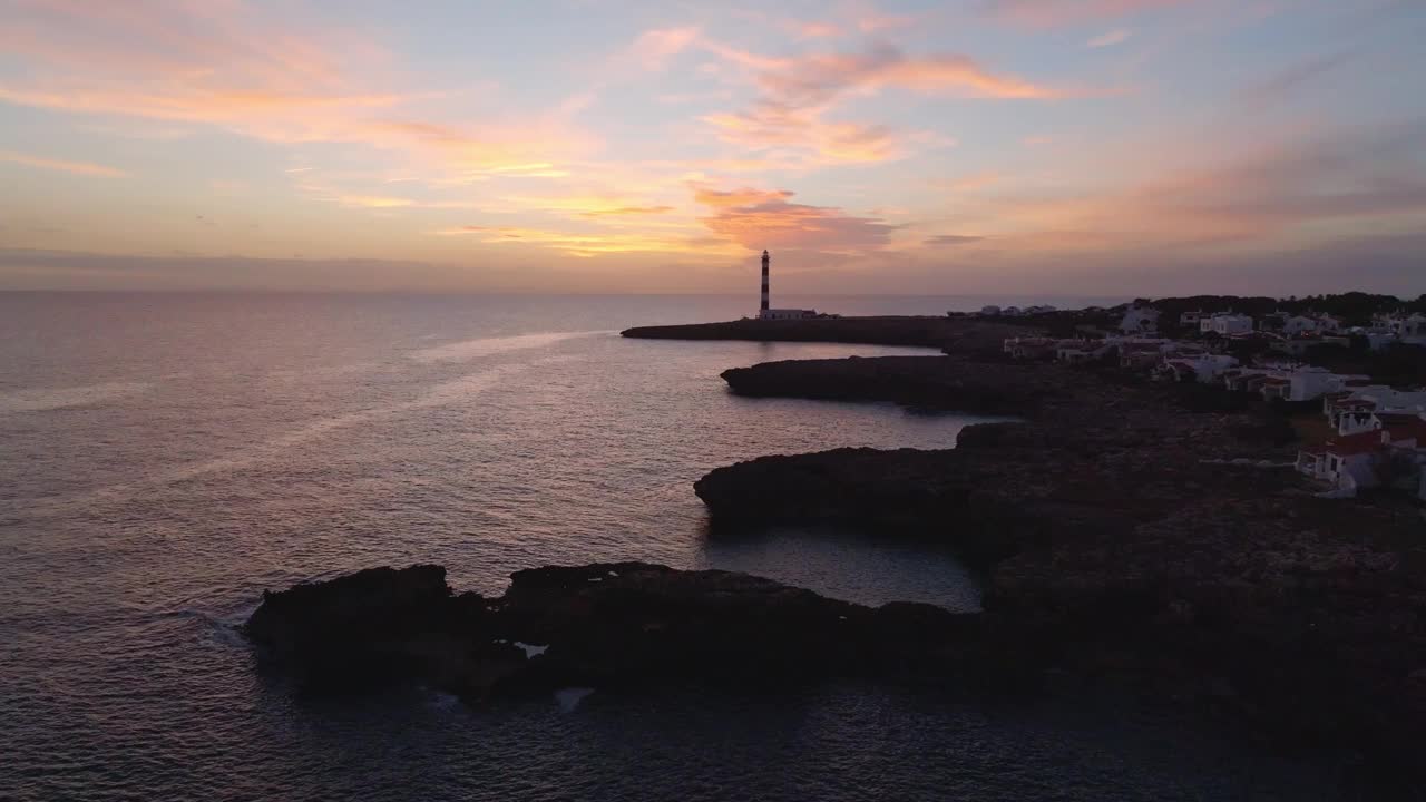 夕阳照耀在梅诺卡岛海滩景观粉红色渐变灯塔背景在西班牙旅游目的地视频素材